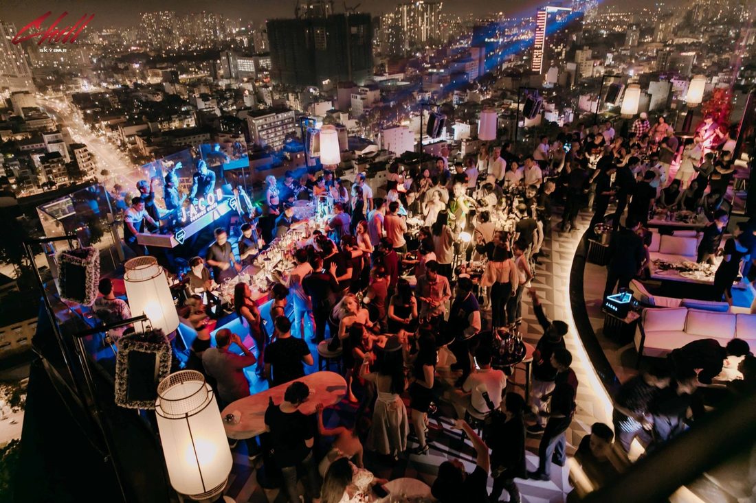 CHILL SKY BAR 天台全景俯拍，DJ 台亮蓝色灯光，人群在吧台前跳舞，右侧是白色沙发卡座区
