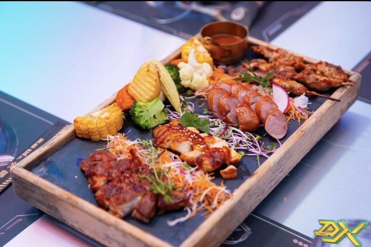 DISTRICT K 韩式烤肉拼盘：梅花肉、酱烧鸡腿、香肠切片、串烧配烤玉米与西兰花，摆在发光的赛博纹台面上