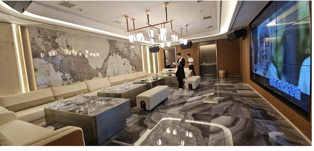 金爵会所长厅包厢：整幅天然石材背景墙、线性吊灯、灰白大理石地面与奶白长沙发