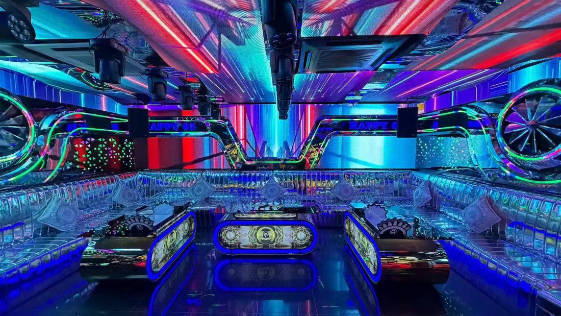 HAPPY 65 KTV 赛博车轮包厢：天花 LED 条屏斜扫光，两侧巨型发光车轮，三张胶囊形茶几