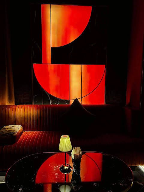 PAPI BAR 店内红橙半圆抽象画墙，画前是一整条丝绒长卡座与黑色大理石圆桌，桌上两盏小褶皱台灯