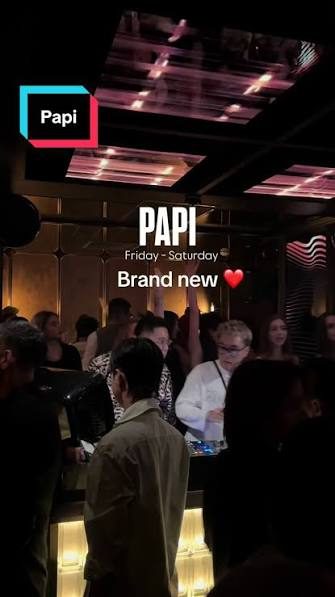 PAPI BAR 周末现场人群实拍：天花板一整片粉红色 LED 条灯，场内站满举手跳动的客人，服务生端着托盘穿行，吧台边缘泛出暖黄灯带